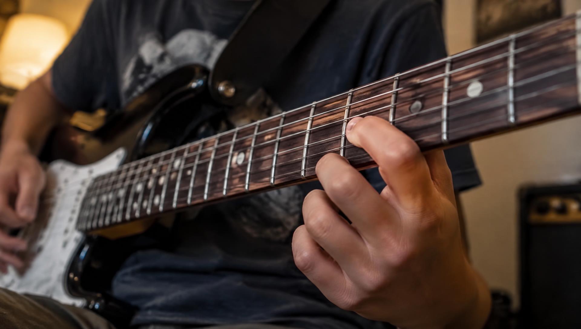 Close-up van vingers die een lick spelen hoog op de hals van een elektrische gitaar